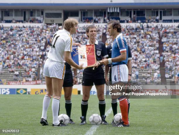 Referee George Courtney of England looks on as the captains of Belgium and France, Jan Ceulemans and Patrick Battiston exchange team pennants prior...