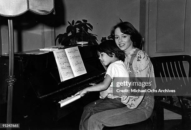 Actress Mackenzie Phillips poses for a portrait session at home holding a baby at the piano on December 3, 1976 in Los Angeles, California.