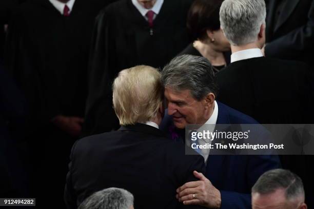 President Donald J. Trump greets Senator Joe Manchin after delivering the State of the Union speech before members of Congress in the House chamber...