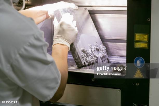 dental technician taking dentures out of 3d powder printer - dental health stock pictures, royalty-free photos & images
