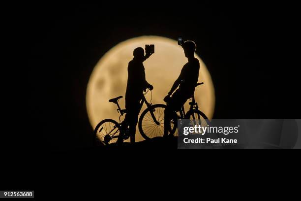 Photo Illustration showing people with bicycles taking photos of the Super moon on January 31, 2018 in Lancelin, Australia. Last seen from Australia...