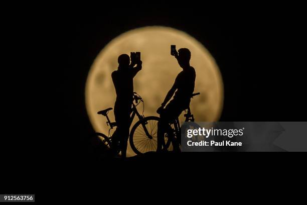 Photo Illustration showing people with bicycles taking photos of the Super moon on January 31, 2018 in Lancelin, Australia. Last seen from Australia...