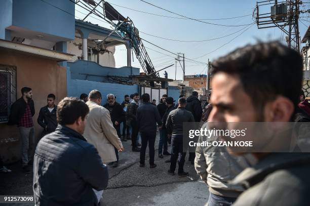 People gather in front of a house after it was hit by a rocket on January 31, 2018 in the Reyhanli district in Hatay, near the Turkey Syria border. A...