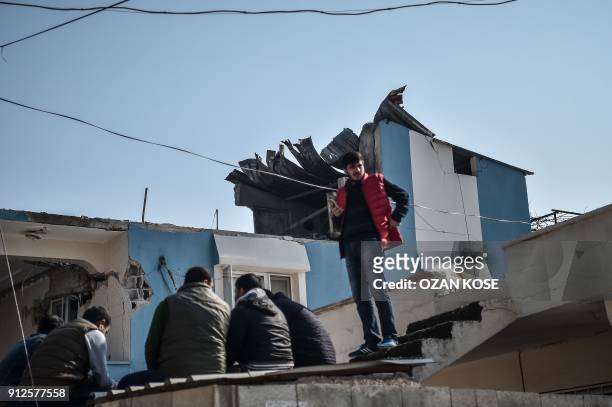 People gather in front of a house after it was hit by a rocket on January 31, 2018 in the Reyhanli district in Hatay, near the Turkey Syria border. A...
