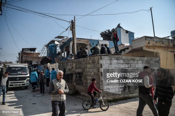 People gather in front of a house after it was hit by a rocket on January 31, 2018 in the Reyhanli district in Hatay, near the Turkey Syria border. A...