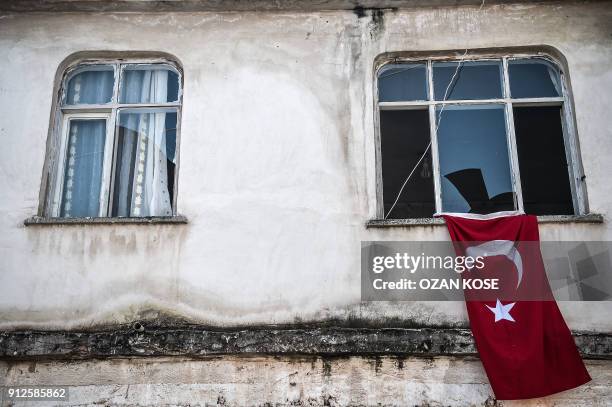 This photo shows a Turkish flag near the damaged windows of a building after a rocket hit an apartment on January 31, 2018 in the Reyhanli district...