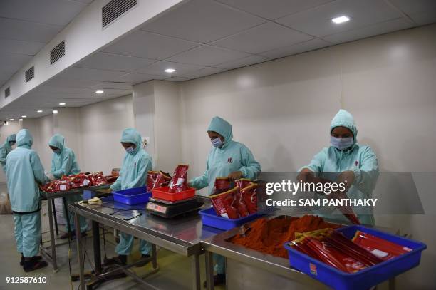 Indian workers pack chilli powder at Hearty Mart Food Product Manufacturers & Packers on the outskirts of Dholka on January 31, 2018. The Indian...