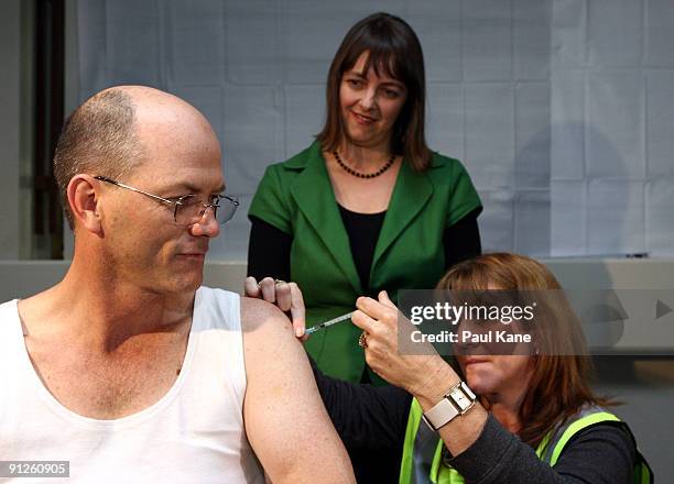 The Minister for Health and Ageing Nicola Roxon looks on as a nurse administers the H1N1 vaccine to Dr Steve Hambleton Vice President of the AMA...