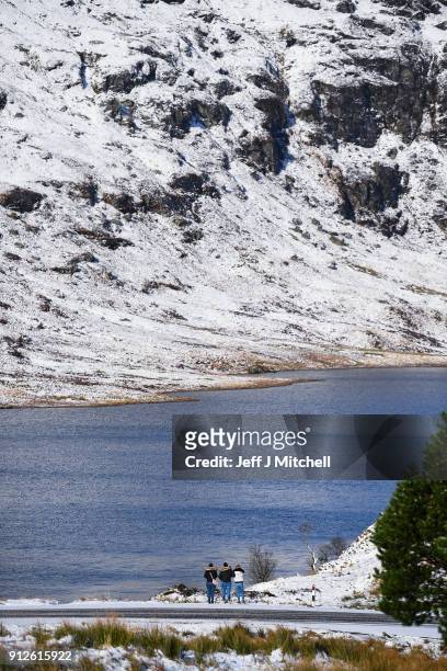 Members of the public take a walk in the snow next to Loch Restil on the A83 Rest and Be Thankful as wintery conditions return on January 31, 2018 in...
