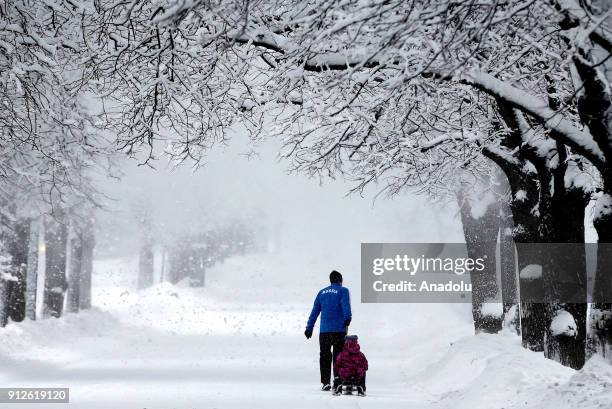 Man pulls his child's sledge during snowfall at the Kosygina Street in Moscow, Russia on January 31, 2018.