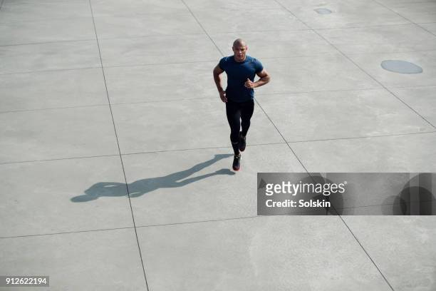 muscular build man running outdoors on concrete surface - flatten the curve imagens e fotografias de stock