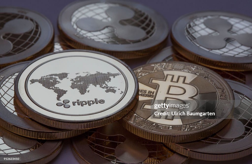 Symbol photo on the topics crypto curreny. the picture shows Ripple coins and a Bitcoin (physical).