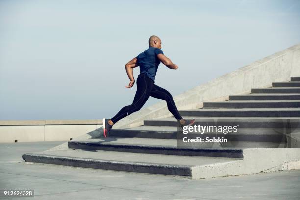 male athlete running up steps outdoors - forward athlete stockfoto's en -beelden