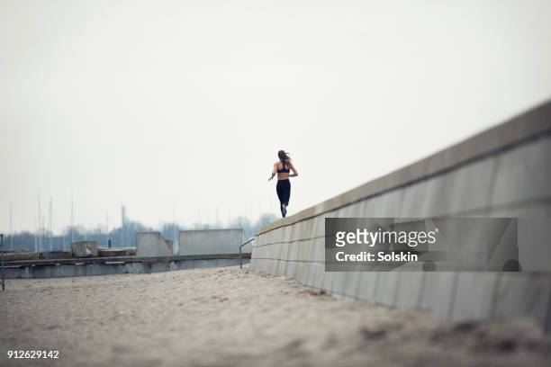 woman running outdoors on concrete wall - flatten the curve imagens e fotografias de stock