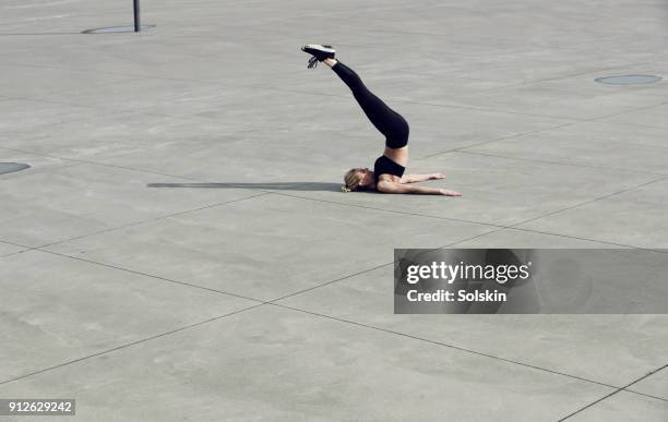 female athlete laying on concrete surface outdoors, stretching legs over head - flatten the curve 個照片及圖片檔
