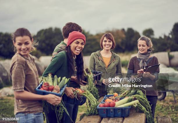 Community farming peers standing together with the allotment produce, laughing