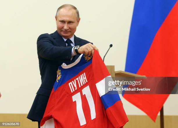 Russian President Vladimir Putin holds up a uniform during his meeting with Olympic athletes who will take part in the upcoming 2018 Pyeongchang...