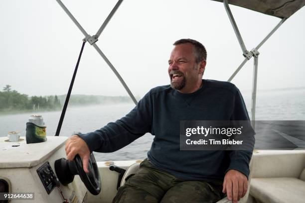 middle age man laughing wile driving pontoon boat - pontoon boat stock pictures, royalty-free photos & images