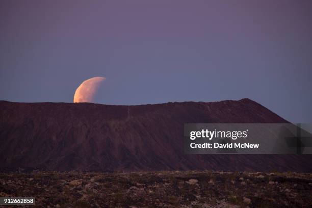 So-called 'super blue blood moon' sets behind Amboy Crater, a cinder cone volcano in the Mojave Desert, at the end of its total eclipse on January...