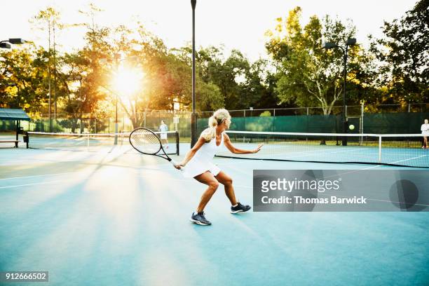 mature female tennis player preparing to hit return during early morning tennis match - tennis 2017 stock-fotos und bilder
