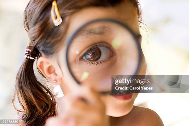 a girl playing with a magnifying  glass - vergrootglas stockfoto's en -beelden