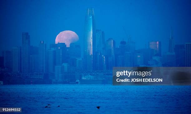 Super blue blood moon sets behind downtown San Francisco, California before dawn on January 31, 2018. For the first time in 35 years, a blue moon...