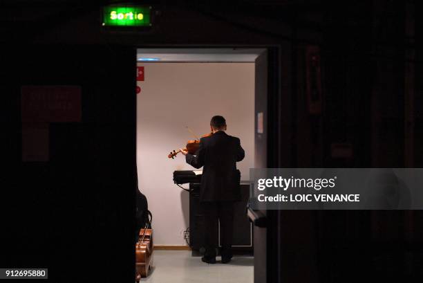 Musician of the Ural Philharmonic Orchestra plays the violin as he practises backstage in a corridor prior to perform on stage during the first day...