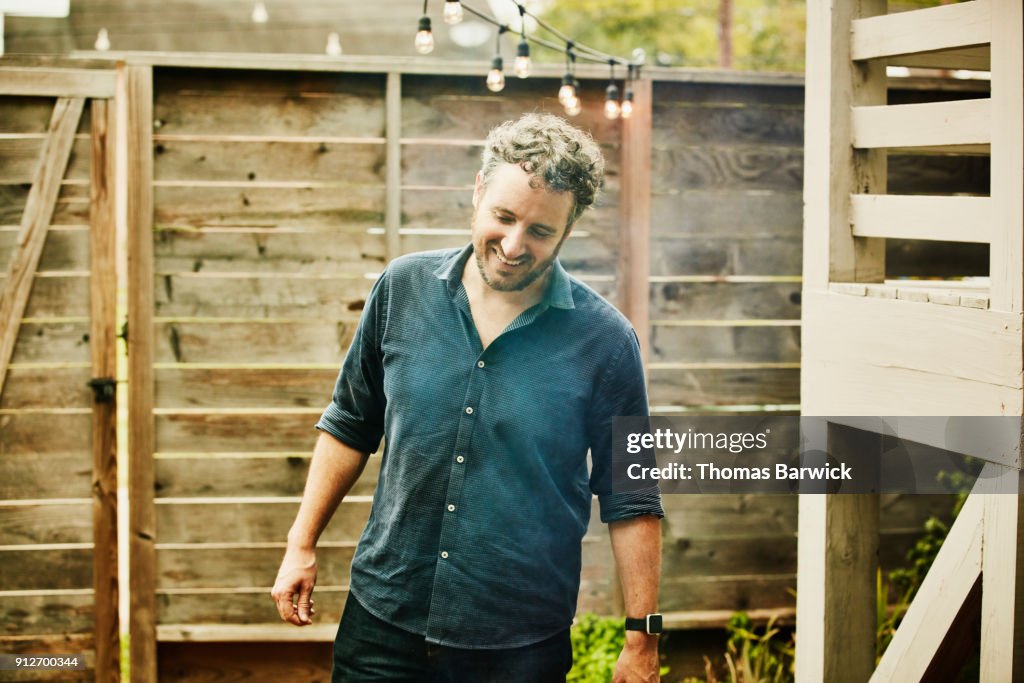 Smiling man preparing barbecue before party with friends on summer evening