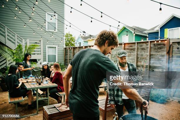 men grilling food for friends during backyard barbecue - barbecue social gathering stock pictures, royalty-free photos & images