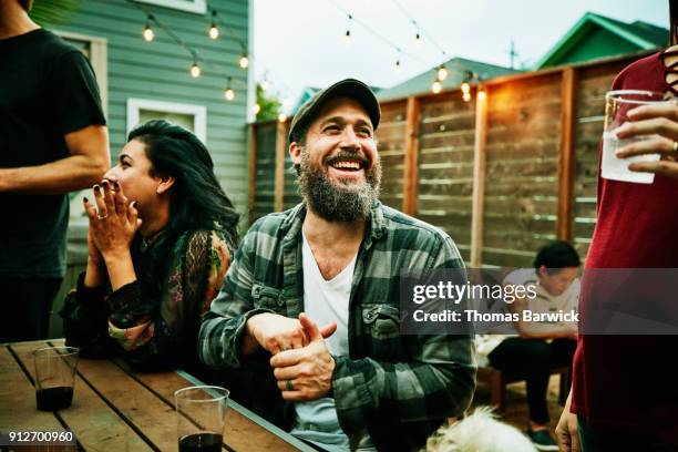 laughing friends hanging out together during backyard dinner party - outdoor entertaining stockfoto's en -beelden