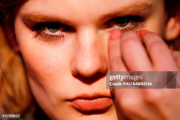 Make-up artist applies an eyelash extention on a model during the 080 Barcelona Fashion Week in Barcelona on January 31, 2018. / AFP PHOTO / PAU...