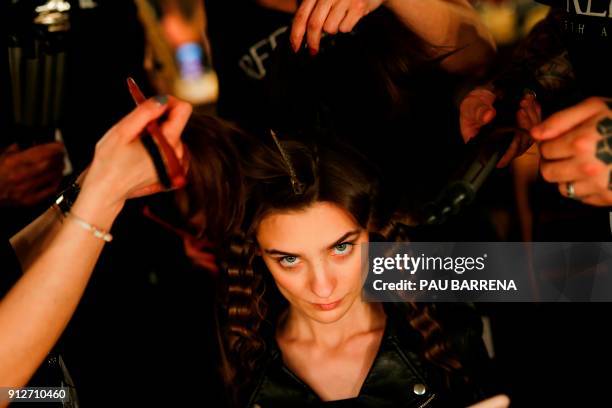 Hairdressers brush a model´s hair during the 080 Barcelona Fashion Week in Barcelona on January 31, 2018. / AFP PHOTO / PAU BARRENA