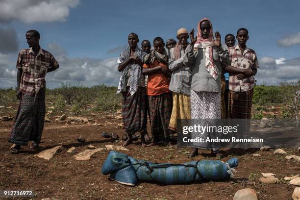 Bashir Bille stands by the body of his son, Noor Bashir as men pray prior to his burial at the Mogor I Maanyi IDP camp in Baidoa, Somalia on May 13,...