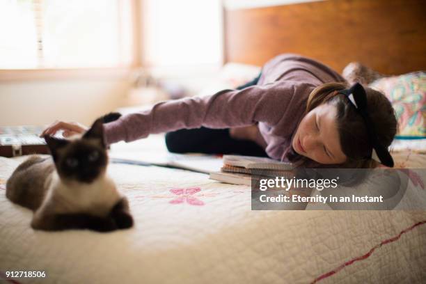 teenage girl wearing cat ears petting her cat in her bedroom - costume cat ears fotografías e imágenes de stock