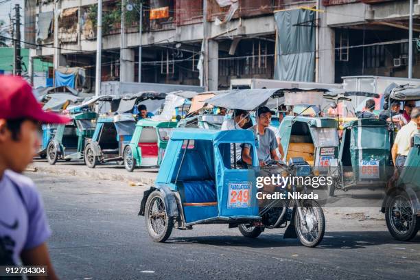 manila street scene with rickshaw driver waiting for clients - filipino tricycle stock pictures, royalty-free photos & images