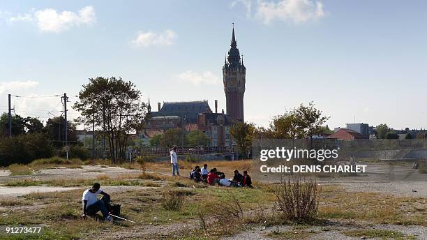 Migrants from Afghanistan sit in a field in Calais, northern France, on September 30 a week after their makeshift camp known as "the jungle" was...