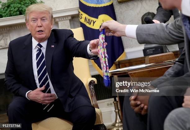President Donald Trump receives a pair of socks as a gift while speaking with American workers in the Oval Office about the recently passed tax...