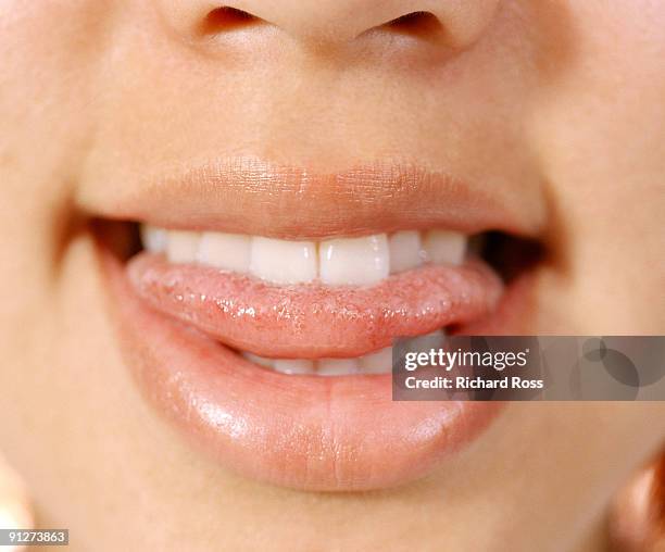 a woman biting her tongue and smiling - mettere fuori la lingua foto e immagini stock