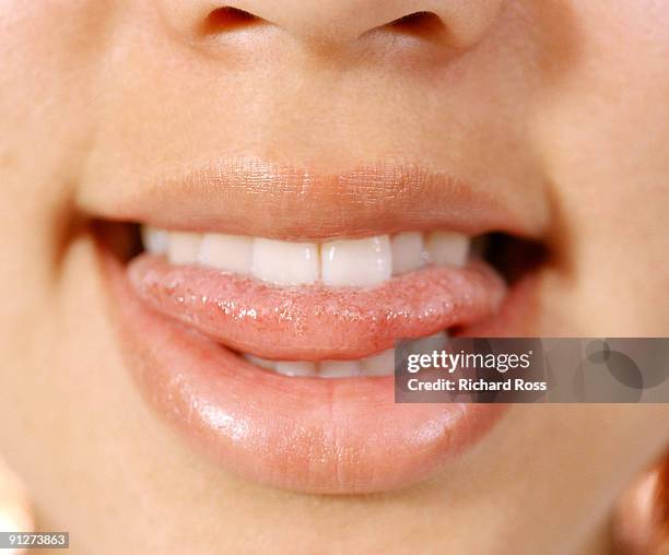 a woman biting her tongue and smiling - tongue foto e immagini stock