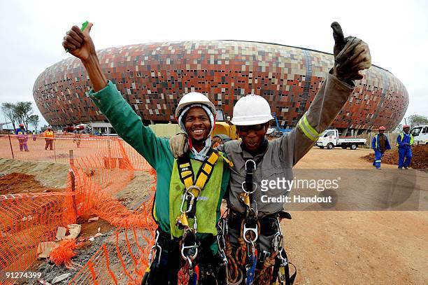 In this handout image provided by the 2010 FIFA World Cup Organising Committee South Africa, workers smile and give a thumbs up during the FIFA...