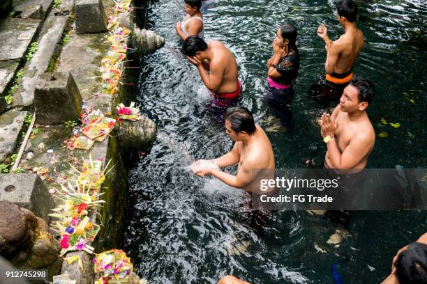 group of people showering under the waterspouts at the tirta empul temple in bali, indonesia - tirta empul temple stock pictures, royalty-free photos & images