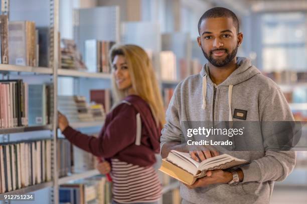 handsome afro american university student studying alone in a campus library - linguistics stock pictures, royalty-free photos & images