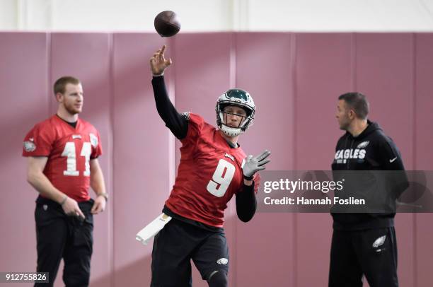 Carson Wentz and quarterbacks coach John DeFilippo of the Philadelphia Eagles looks on as teammate Nick Foles passes the ball during Super Bowl LII...