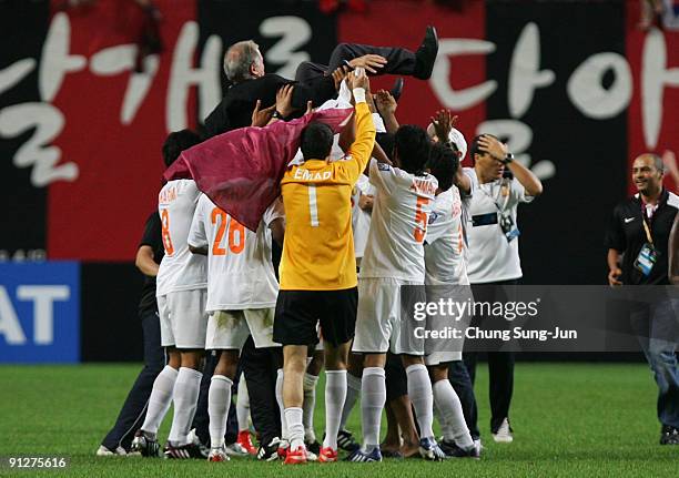 Umm Salal's players toss their coach Gerard Auguste Gili as they celebrate their advance to the semi-final after their AFC Champions League match...