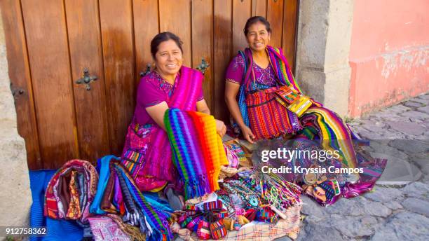 mayan women selling handmade textiles and souvenirs, antigua, guatemala - custom fotografías e imágenes de stock