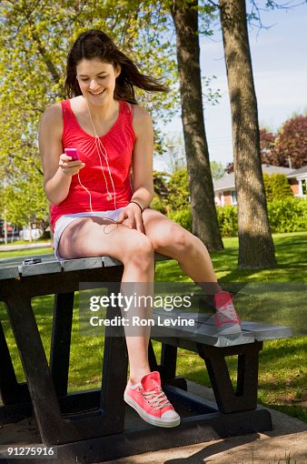 Teen girl in park with pink sneakers using mp3 player Teen girl in park with pink sneakers using mp3 player