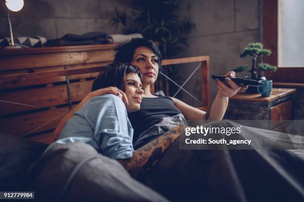 watching tv in bed - lesbian bed stock pictures, royalty-free photos & images