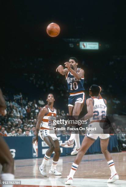 Norm Nixon of the Los Angeles Clippers passes the ball over the top of Dudley Bradley of the Washington Bullets during an NBA basketball game circa...