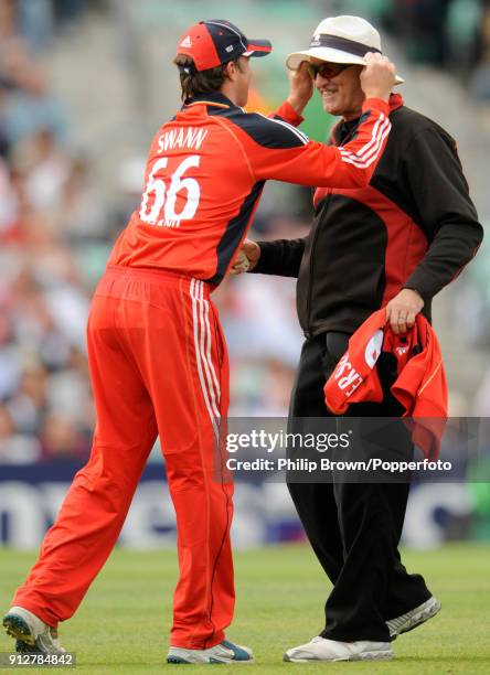 England's Graeme Swann puts umpire Tony Hill's hat back on his head after it blew off during the 1st NatWest Series One Day International between...