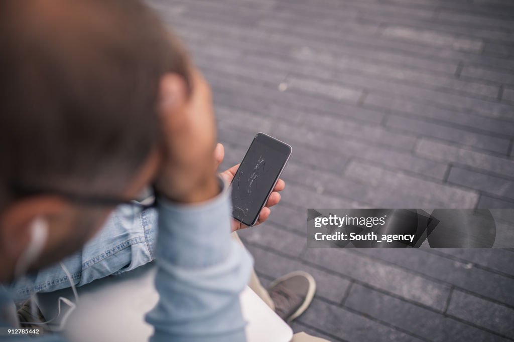 Homem descontente com smartphone quebrado